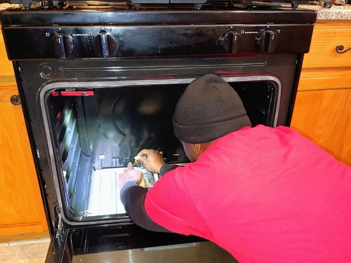 Gas oven repair in Decatur GA - Decatur Solution Works technician repairing a gas range oven